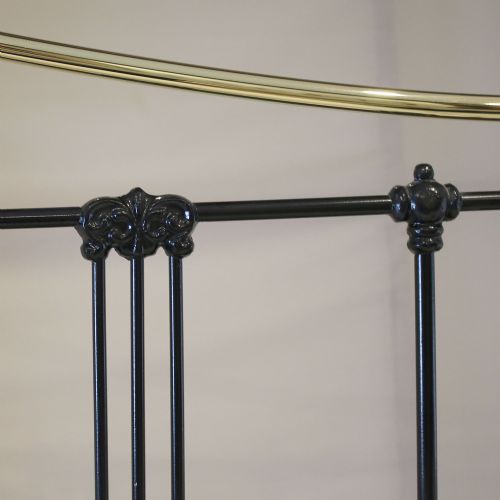 fig 3. A Victorian-style black iron and brass bedstead with vertical spindles, decorative brass finials, and a curved brass top rail.