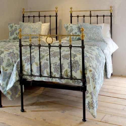 fig 1. A matching pair of black cast iron single bed frames featuring vertical spindles and polished brass top rails with decorative finials.
