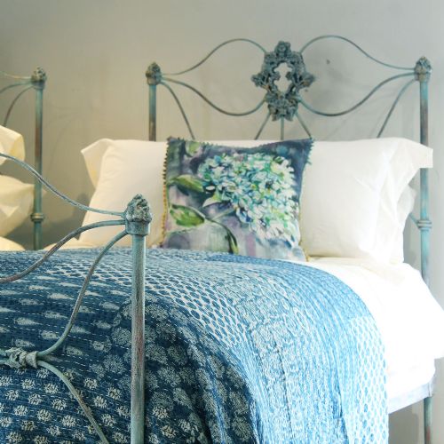 fig 1. A matching pair of single cast iron beds featuring scrollwork headboards and footboards finished in a blue verdigris patina.
