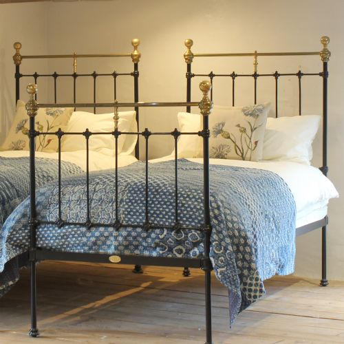 fig 1. A matching pair of Victorian black cast iron single beds featuring vertical spindles and polished brass top rails with urn finials.