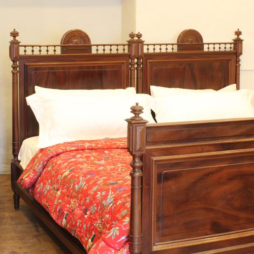 fig 1. A pair of matching nineteenth-century French mahogany single beds featuring spindled headboards and panelled footboards placed side-by-side.