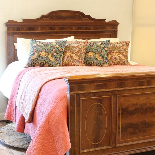 fig 1. An antique French mahogany bed frame with flame mahogany veneered panels, boxwood stringing, a curved crest headboard, and a matching panelled footboard.