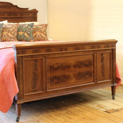 fig 2. An antique French mahogany bed frame with flame mahogany veneered panels, boxwood stringing, a curved crest headboard, and a matching panelled footboard.