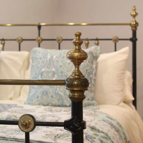 fig 2. A Victorian black painted cast iron and brass king-size bedstead featuring turned brass finials, vertical spindles, and a central brass diamond motif.