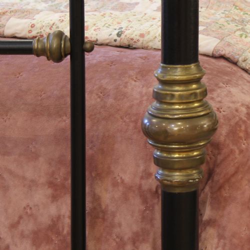 fig 1. An antique king size bedstead featuring black painted iron vertical spindles topped with decorative brass rails, turned collars, and corner finials.