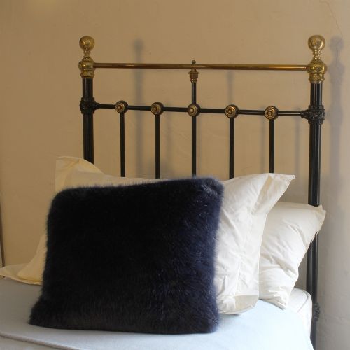 fig 2. A Victorian single bedstead featuring a black iron frame, vertical spindles, brass accent roundels, and polished brass top rails with brass finials.