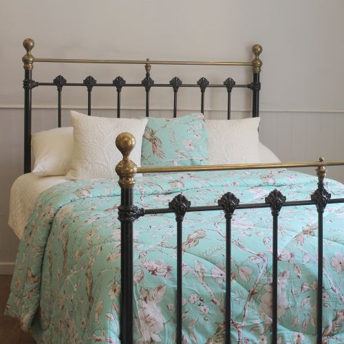 fig 1. A Victorian black cast iron double bed frame featuring brass top rails, brass corner finials, and vertical iron spindles with ornate cast decorative joints.