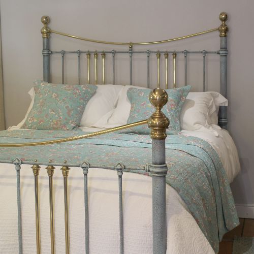 fig 1. An antique king size bedstead featuring a light blue verdigris painted finish on iron spindles, accented by brass top rails and brass finials.