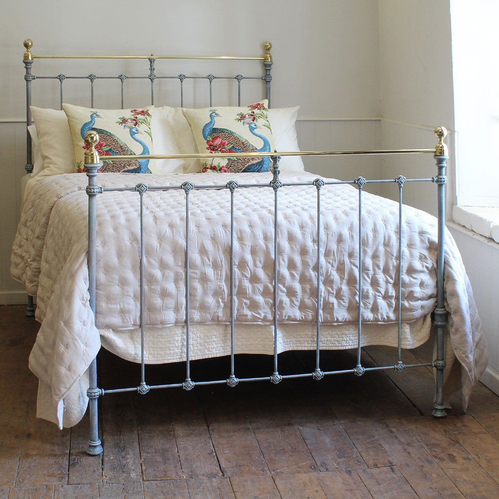 A Victorian style metal double bed frame with vertical iron spindles, brass top rails, and brass finials.