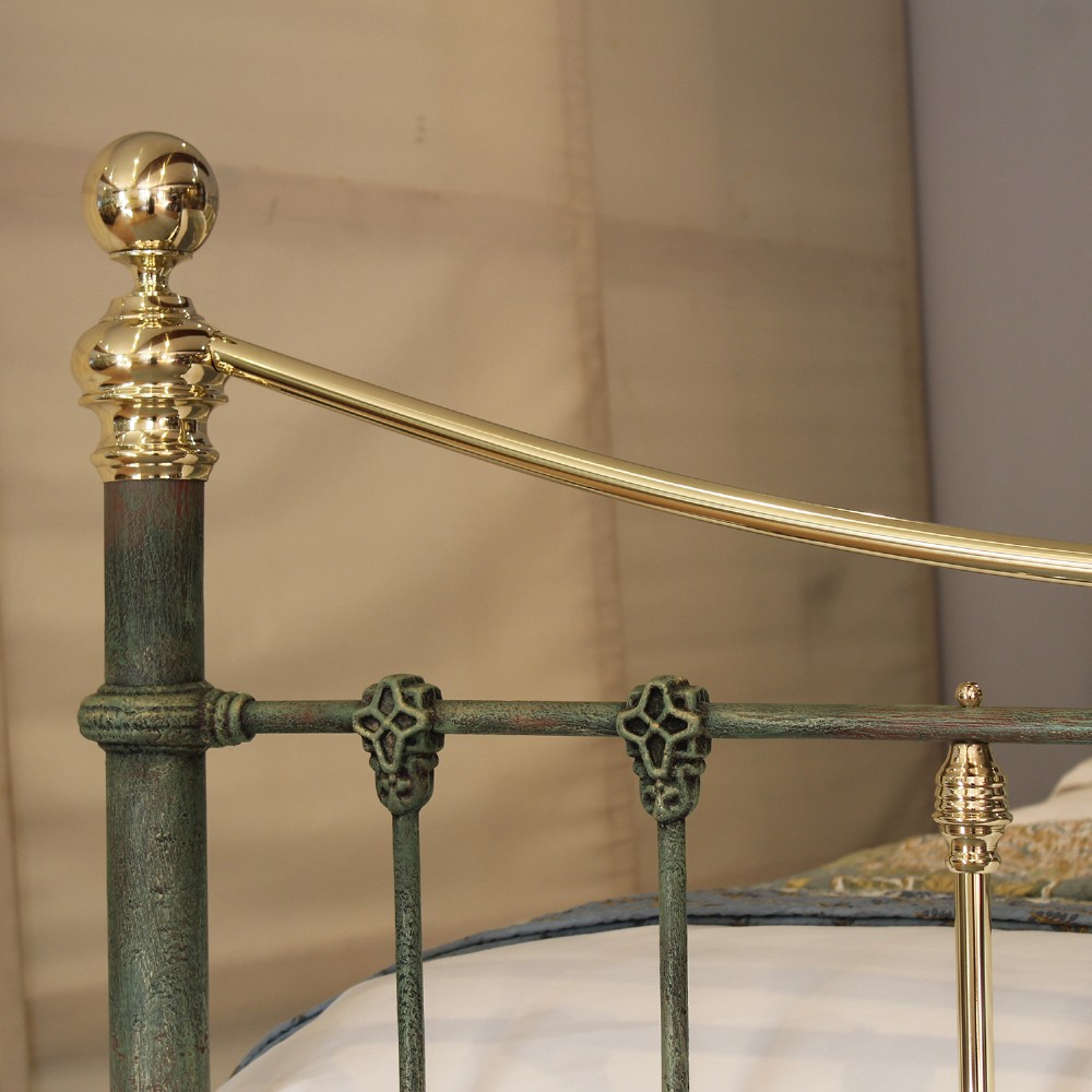 A king-size green painted metal bedstead featuring curved brass top rails, polished brass finials, and vertical central spindles. View V