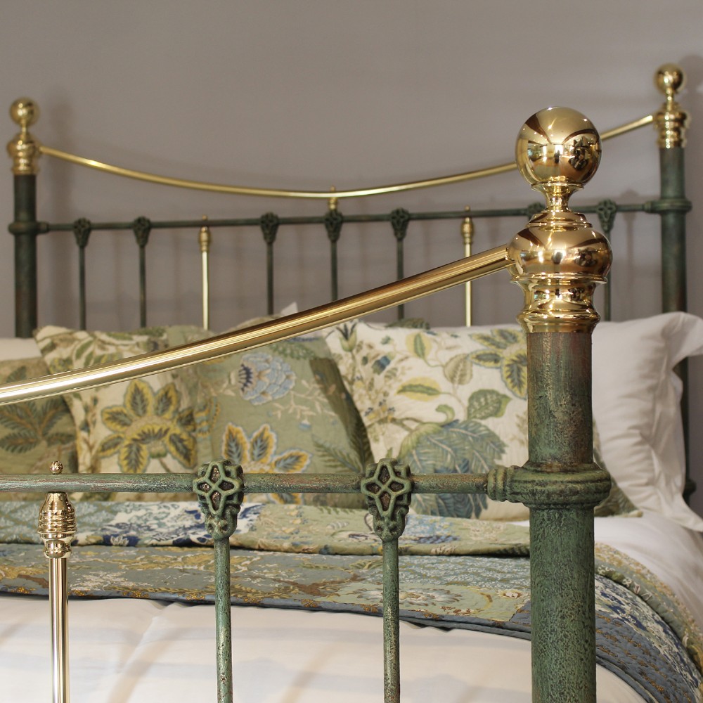 A king-size green painted metal bedstead featuring curved brass top rails, polished brass finials, and vertical central spindles. View VI