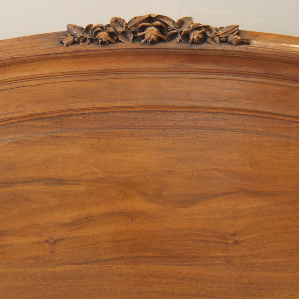 A king-size carved mahogany bed frame featuring an arched headboard and a carved floral wreath motif on the footboard. View II