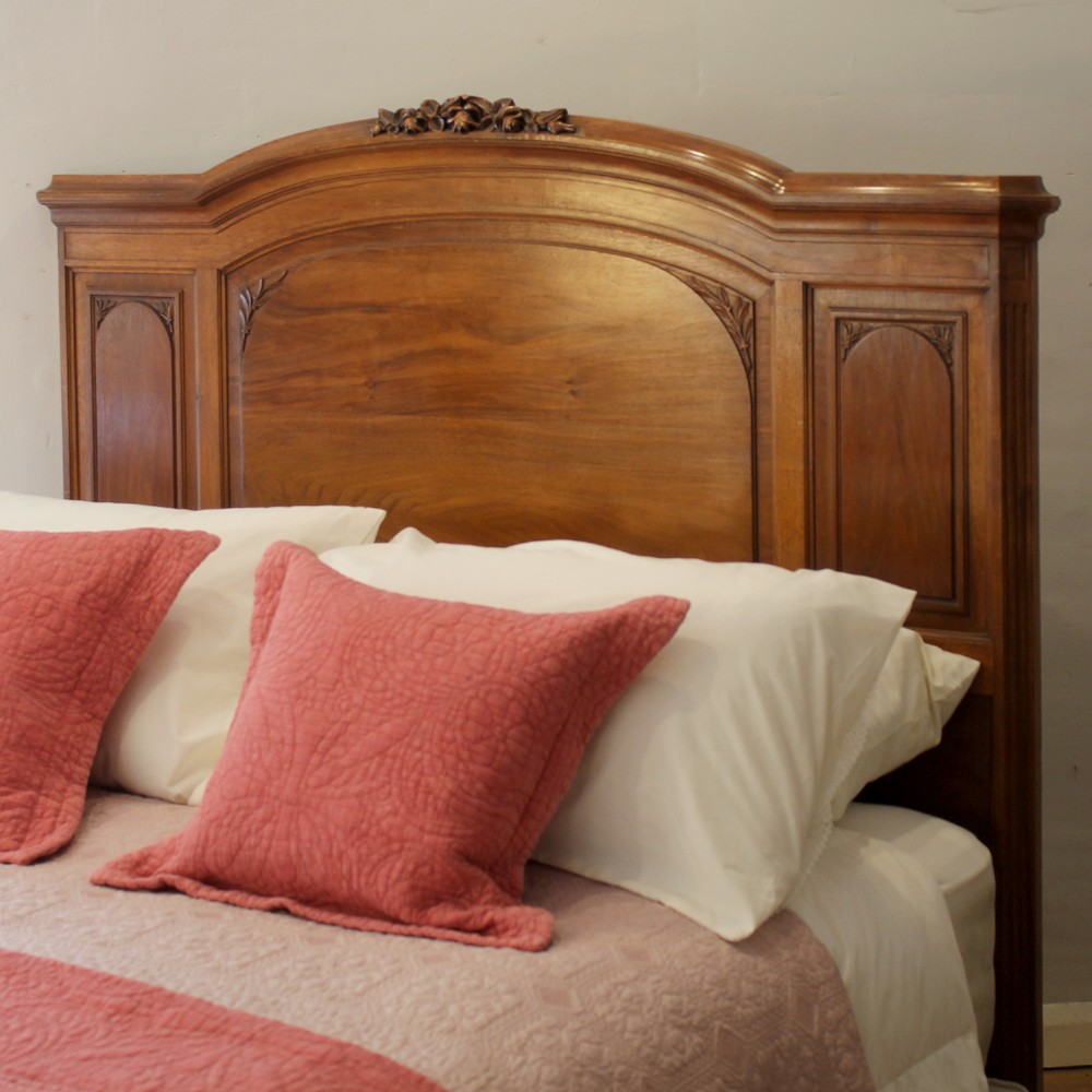 A king-size carved mahogany bed frame featuring an arched headboard and a carved floral wreath motif on the footboard. View IV