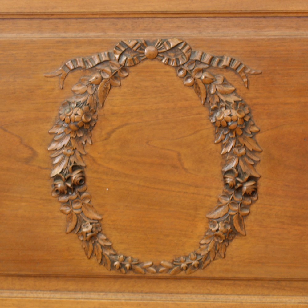 A king-size carved mahogany bed frame featuring an arched headboard and a carved floral wreath motif on the footboard. View VII