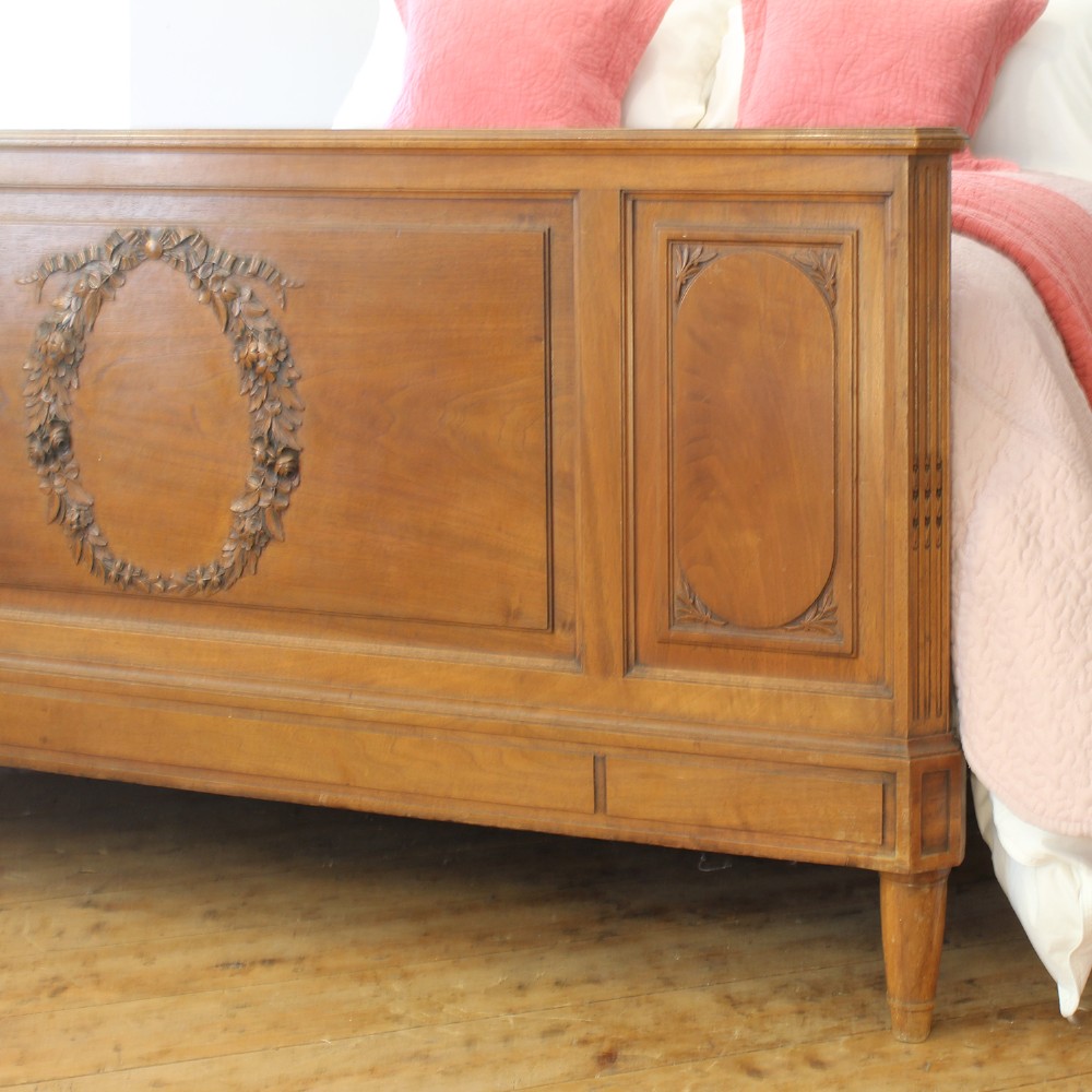 A king-size carved mahogany bed frame featuring an arched headboard and a carved floral wreath motif on the footboard. View VIII