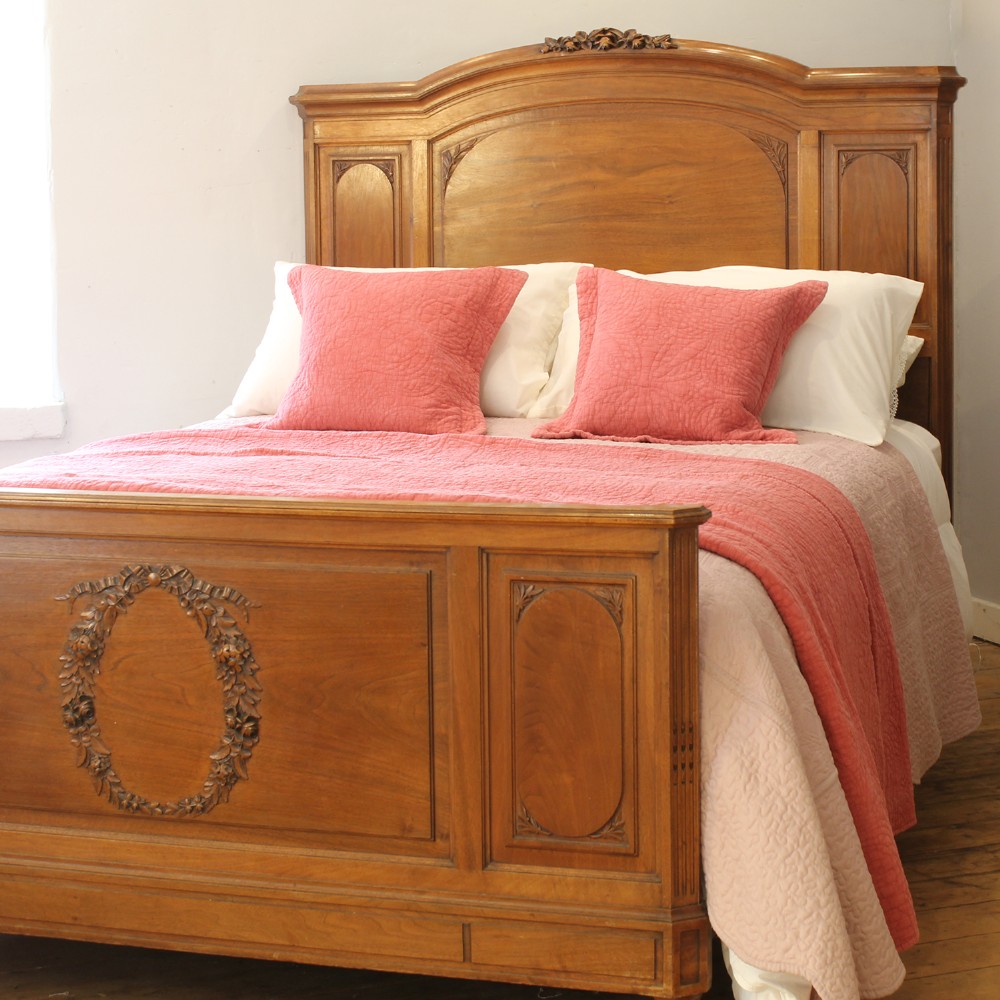 A king-size carved mahogany bed frame featuring an arched headboard and a carved floral wreath motif on the footboard. View IX