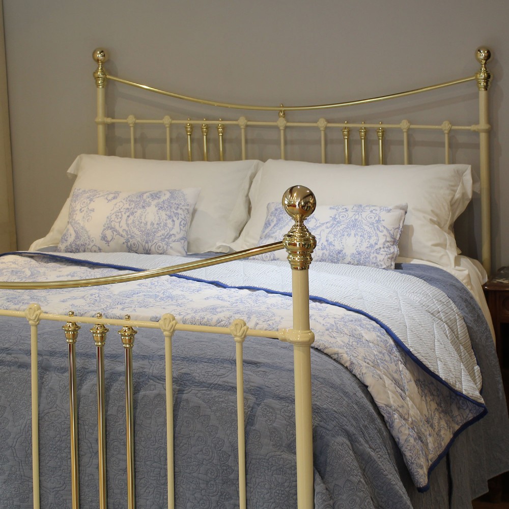 An antique king-size cream-painted metal bedstead featuring polished brass top rails, brass finials, and vertical spindle detailing. View II