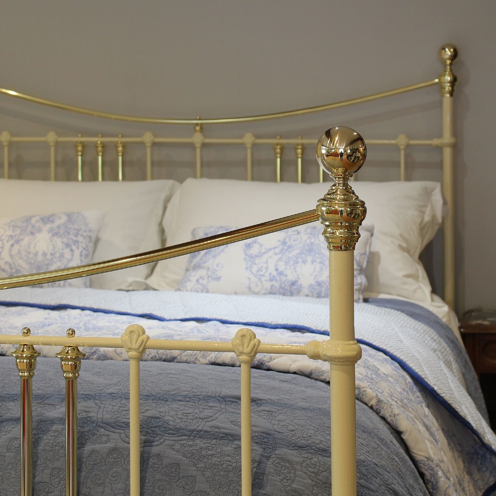 An antique king-size cream-painted metal bedstead featuring polished brass top rails, brass finials, and vertical spindle detailing. View III
