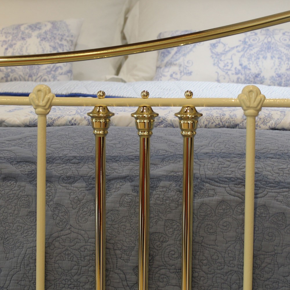 An antique king-size cream-painted metal bedstead featuring polished brass top rails, brass finials, and vertical spindle detailing. View IV