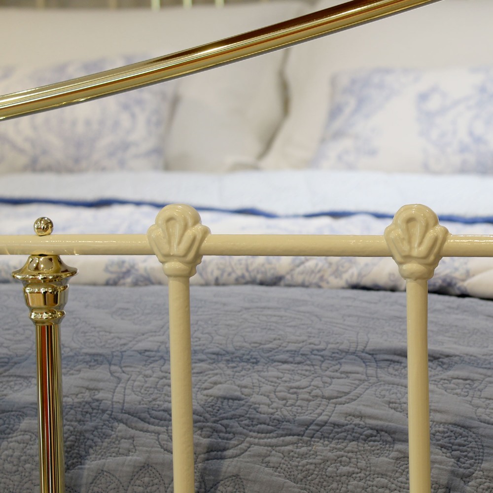 An antique king-size cream-painted metal bedstead featuring polished brass top rails, brass finials, and vertical spindle detailing. View VII