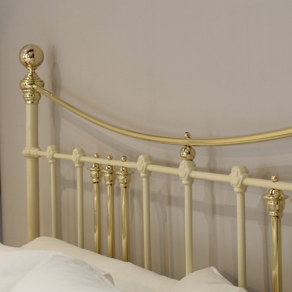 An antique king-size cream-painted metal bedstead featuring polished brass top rails, brass finials, and vertical spindle detailing. View IX