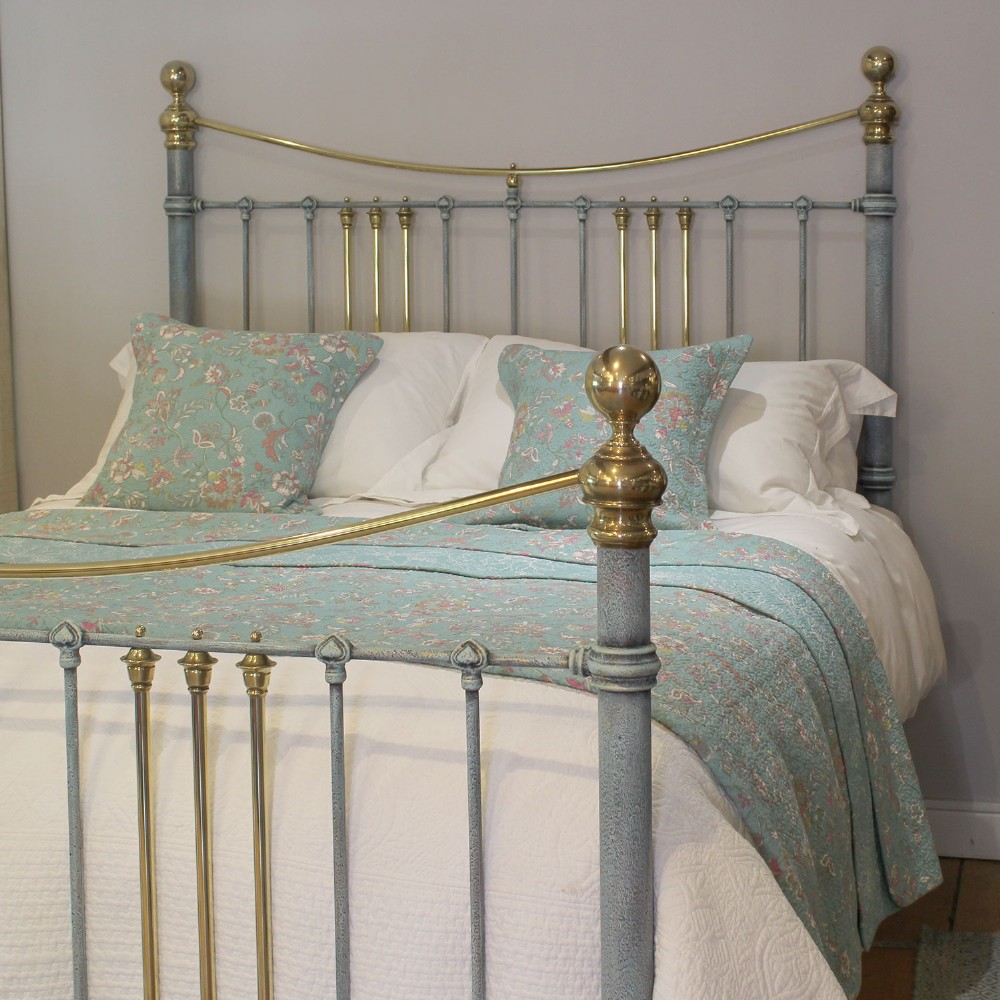 An antique king size bedstead featuring a light blue verdigris painted finish on iron spindles, accented by brass top rails and brass finials. View II