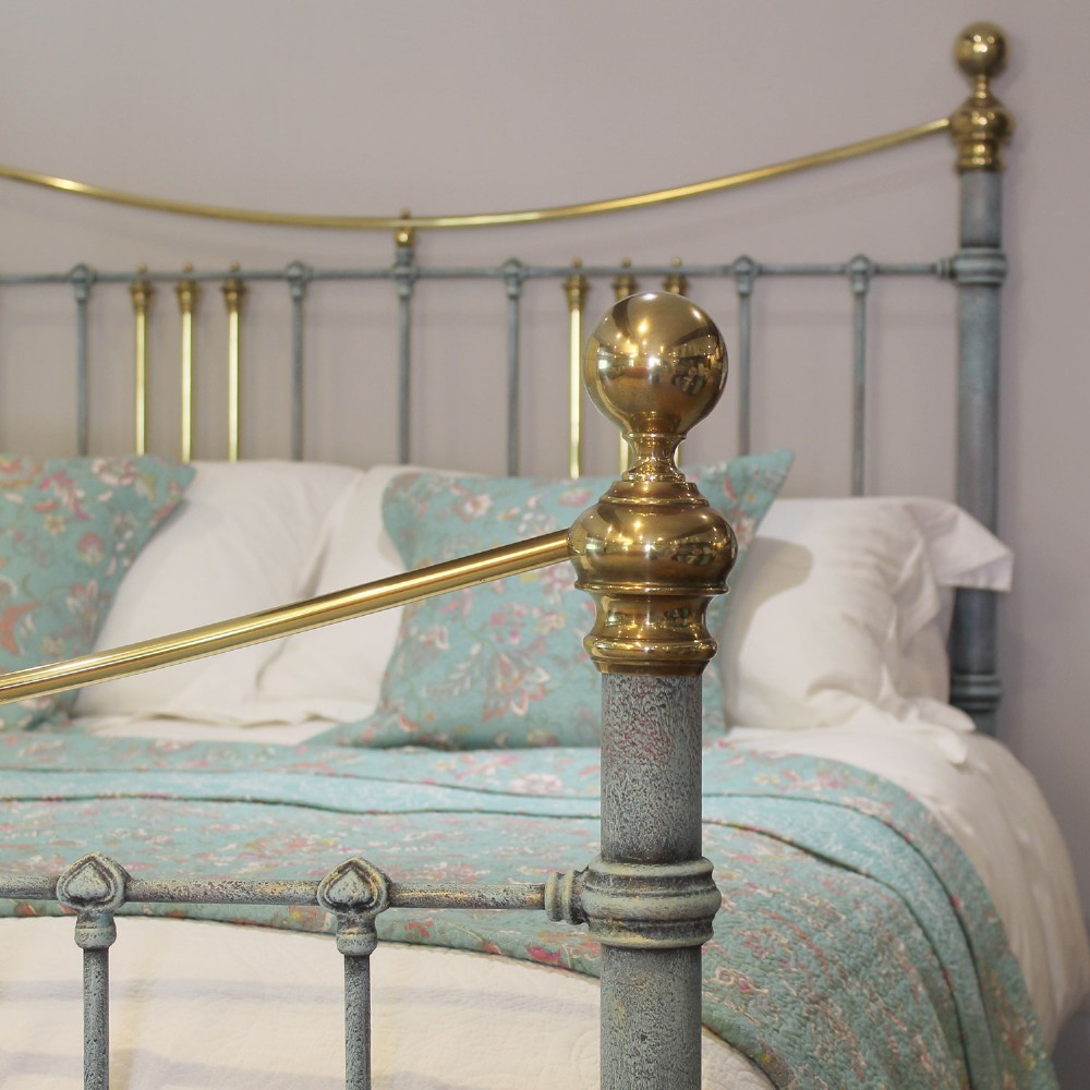 An antique king size bedstead featuring a light blue verdigris painted finish on iron spindles, accented by brass top rails and brass finials. View III