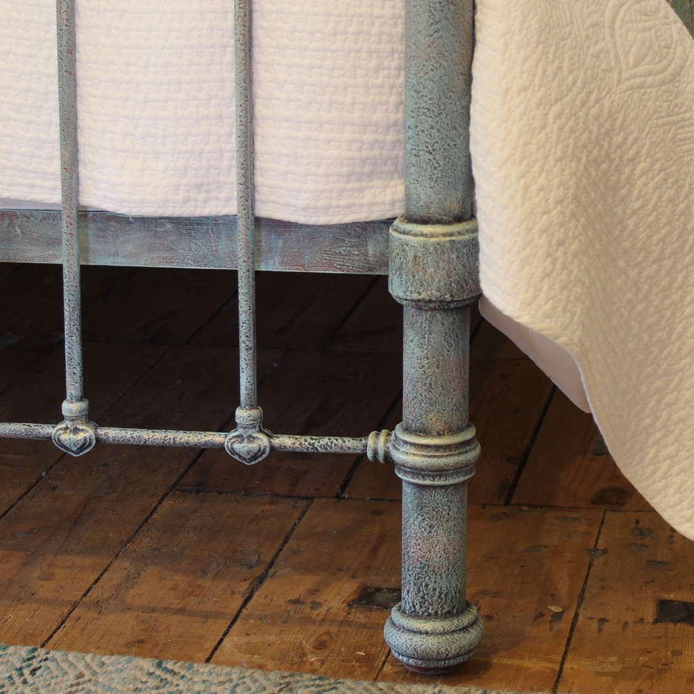 An antique king size bedstead featuring a light blue verdigris painted finish on iron spindles, accented by brass top rails and brass finials. View IV
