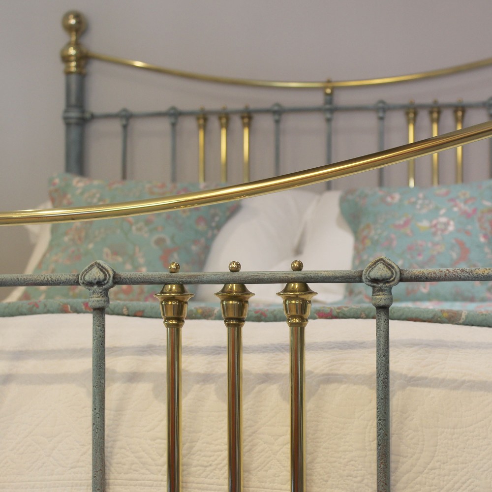 An antique king size bedstead featuring a light blue verdigris painted finish on iron spindles, accented by brass top rails and brass finials. View V