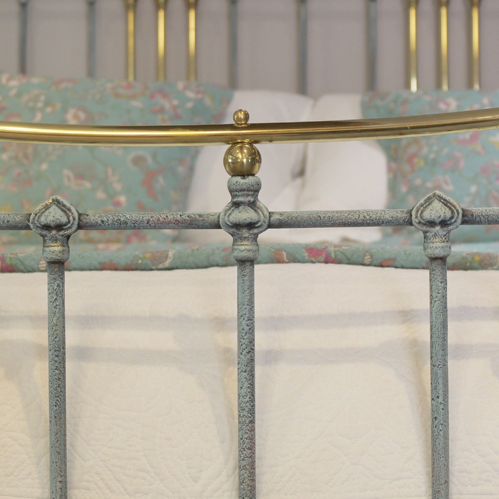 An antique king size bedstead featuring a light blue verdigris painted finish on iron spindles, accented by brass top rails and brass finials. View VI