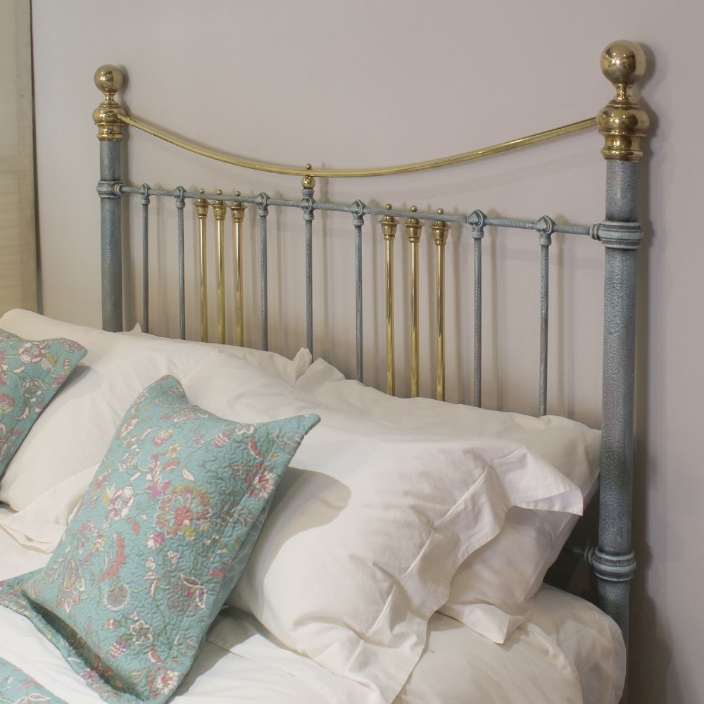 An antique king size bedstead featuring a light blue verdigris painted finish on iron spindles, accented by brass top rails and brass finials. View VII