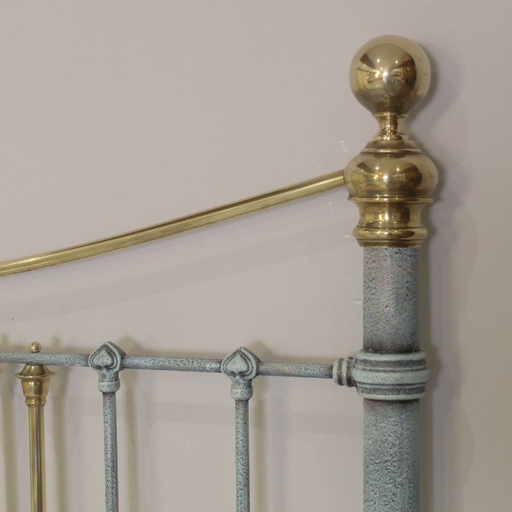 An antique king size bedstead featuring a light blue verdigris painted finish on iron spindles, accented by brass top rails and brass finials. View VIII