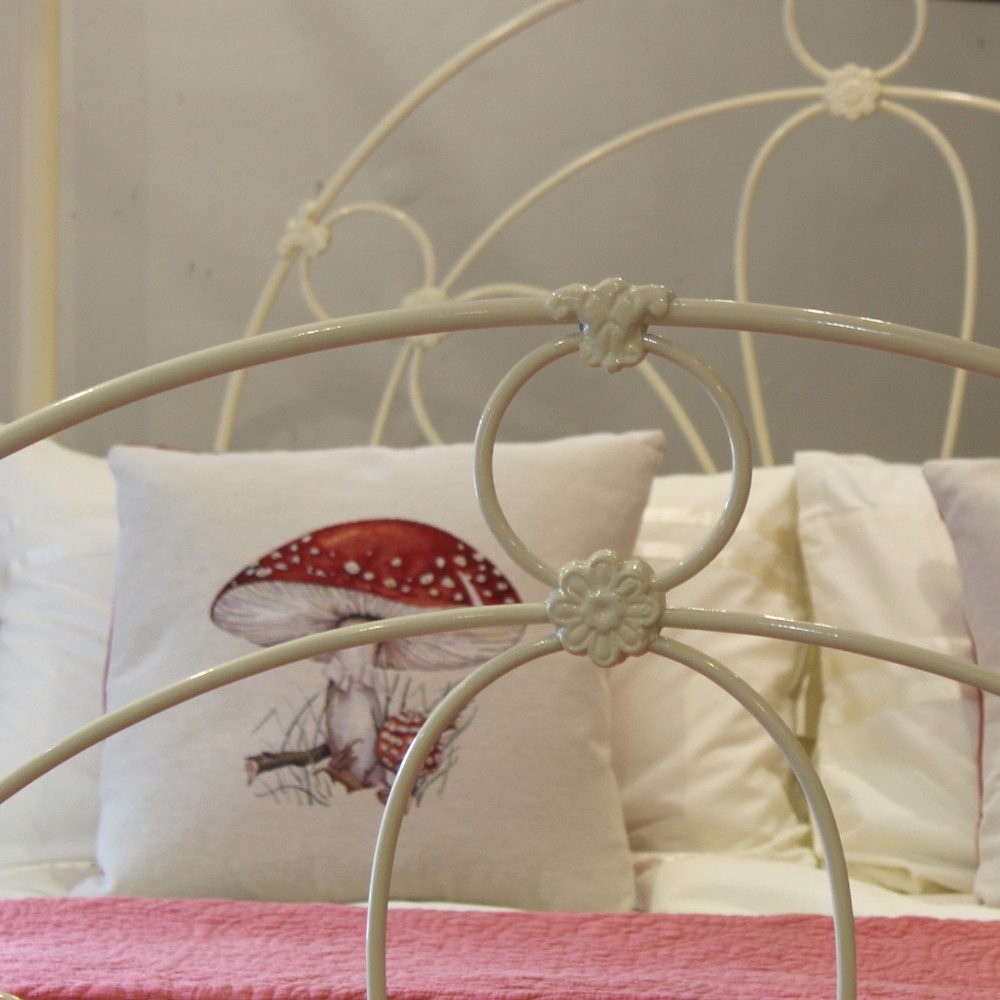 A cream-painted metal four-poster bed frame featuring an arched sunburst motif on the headboard and footboard topped with brass finials. View III
