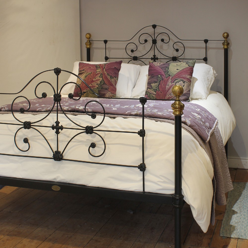 A black wrought iron king-size bed frame featuring decorative scrollwork on the headboard and footboard, topped with brass corner finials. View II