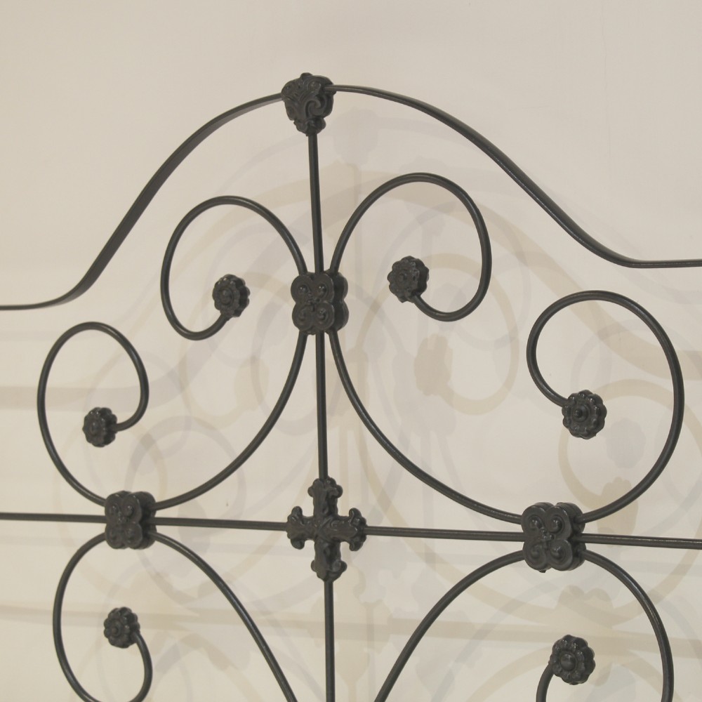 A black wrought iron king-size bed frame featuring decorative scrollwork on the headboard and footboard, topped with brass corner finials. View VIII