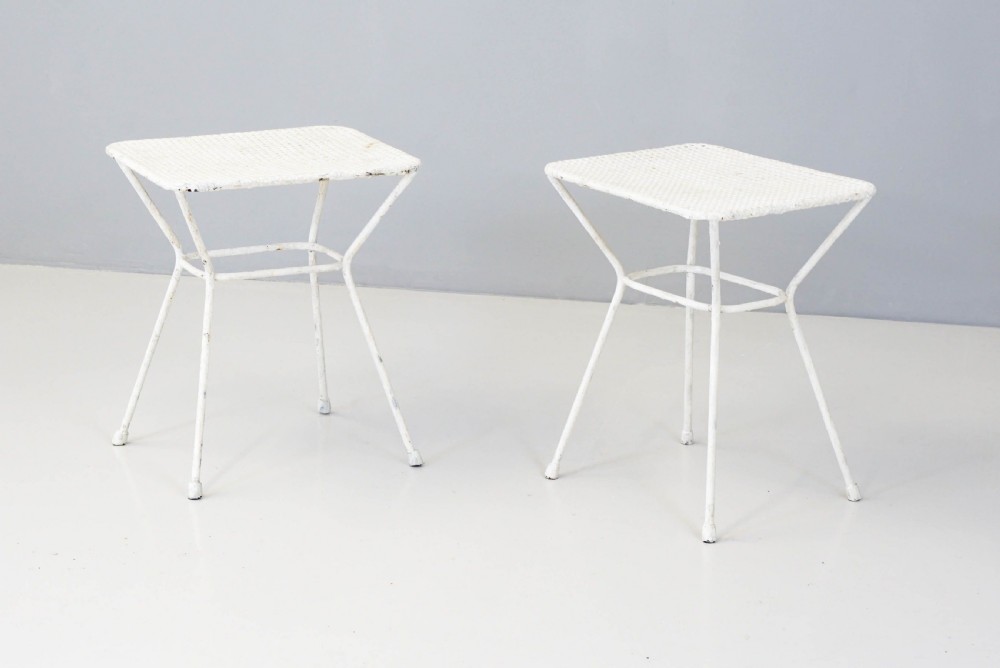 A pair of mid-century white painted metal side tables with perforated mesh rectangular tops and splayed tubular legs connected by a central circular ring. View II