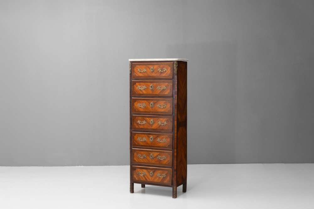 A tall, narrow French semainier chest of drawers featuring geometric wood parquetry, seven drawers, gilt bronze hardware, and a white marble top. View III