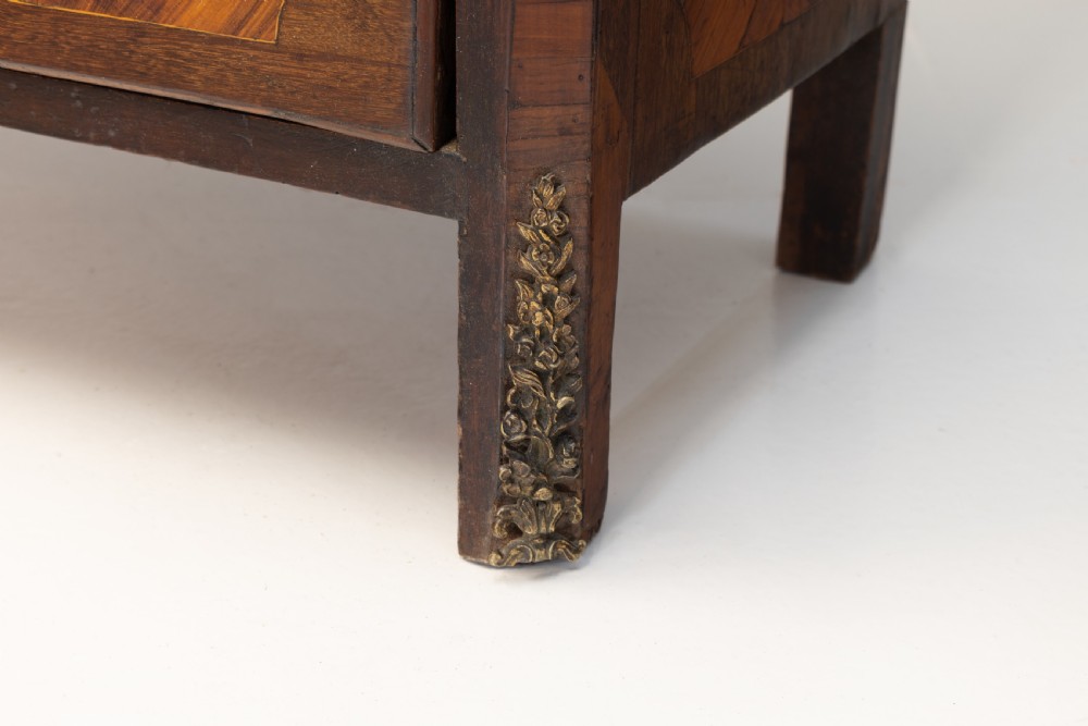 A tall, narrow French semainier chest of drawers featuring geometric wood parquetry, seven drawers, gilt bronze hardware, and a white marble top. View VII