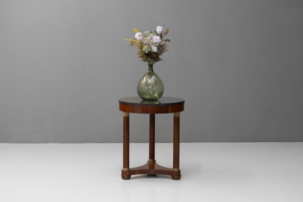 A French Empire style circular mahogany gueridon table featuring a dark marble top supported by three cylindrical columns on a tri-form base. View II