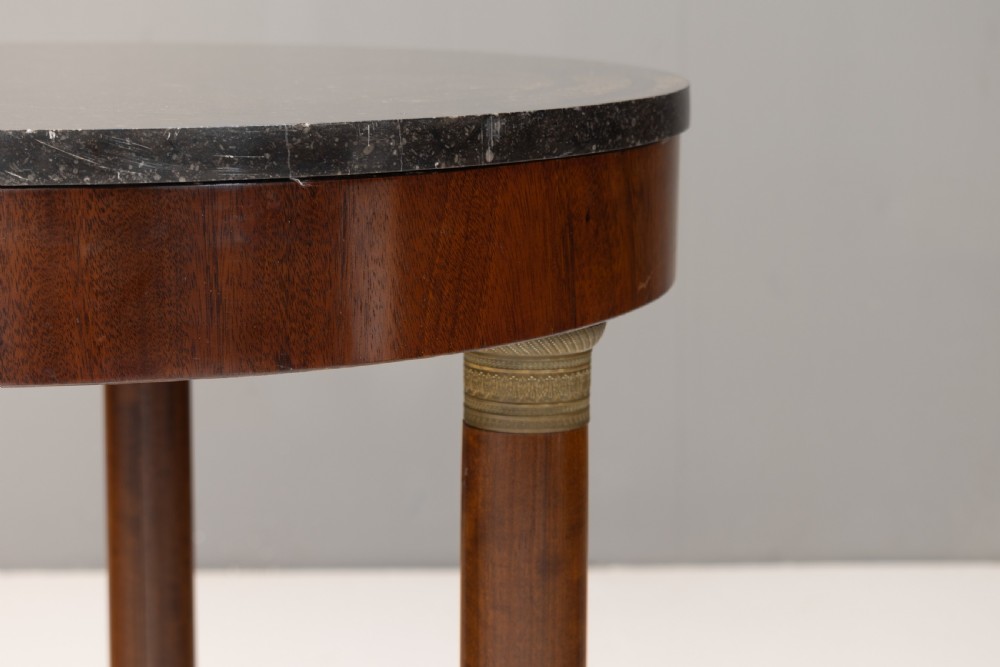 A French Empire style circular mahogany gueridon table featuring a dark marble top supported by three cylindrical columns on a tri-form base. View V