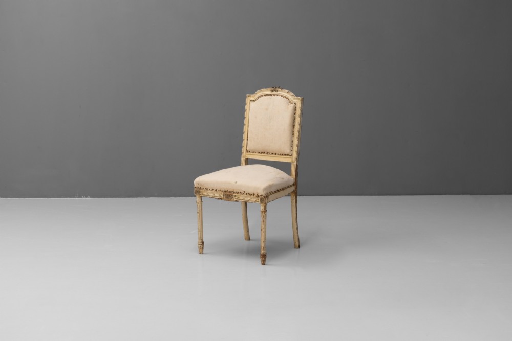 A pair of French Louis XVI style side chairs featuring distressed cream painted frames, tapered fluted legs, and neutral fabric upholstery. View III
