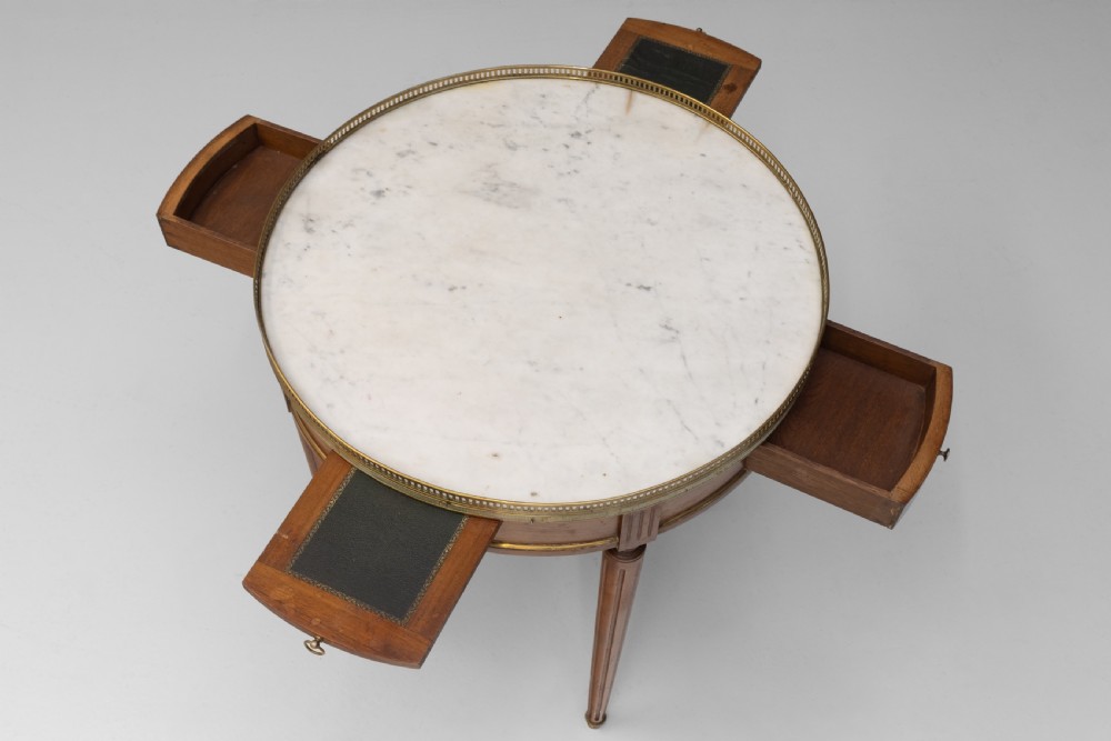 A circular Louis XVI style mahogany bouillotte table featuring a white marble top with a pierced brass gallery rim and fluted tapered legs. View IV