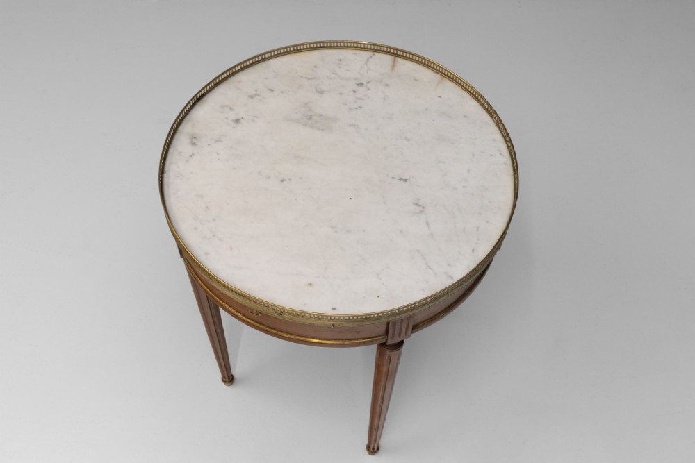 A circular Louis XVI style mahogany bouillotte table featuring a white marble top with a pierced brass gallery rim and fluted tapered legs. View V