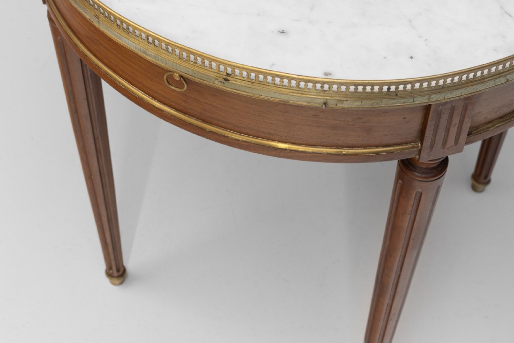 A circular Louis XVI style mahogany bouillotte table featuring a white marble top with a pierced brass gallery rim and fluted tapered legs. View VI