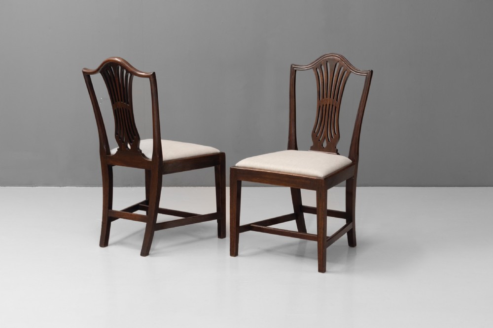 A set of six dark mahogany dining chairs featuring pierced splat backs, square stretchered legs, and light cream upholstered drop-in seats. View III