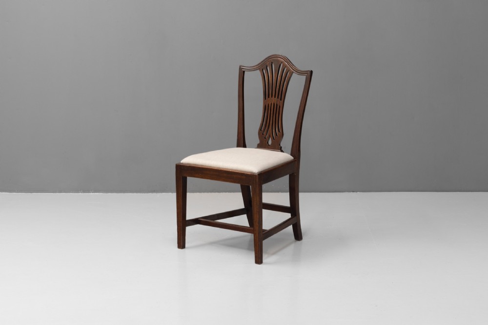 A set of six dark mahogany dining chairs featuring pierced splat backs, square stretchered legs, and light cream upholstered drop-in seats. View IV