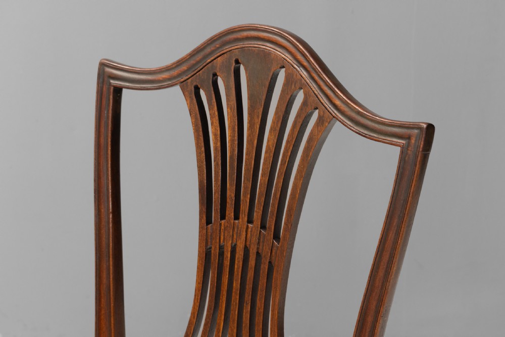 A set of six dark mahogany dining chairs featuring pierced splat backs, square stretchered legs, and light cream upholstered drop-in seats. View V