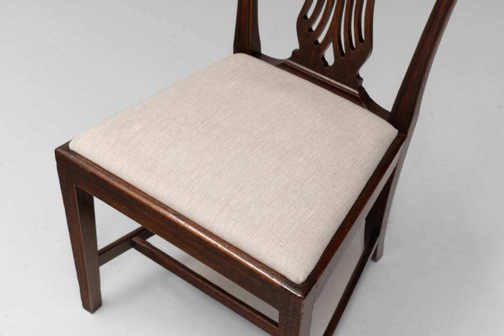 A set of six dark mahogany dining chairs featuring pierced splat backs, square stretchered legs, and light cream upholstered drop-in seats. View VI