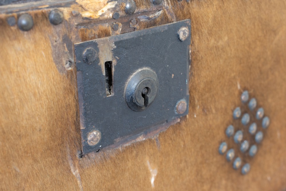 An antique domed-top storage trunk covered in natural brown hide, detailed with decorative iron studding and a central iron lockplate. View VIII