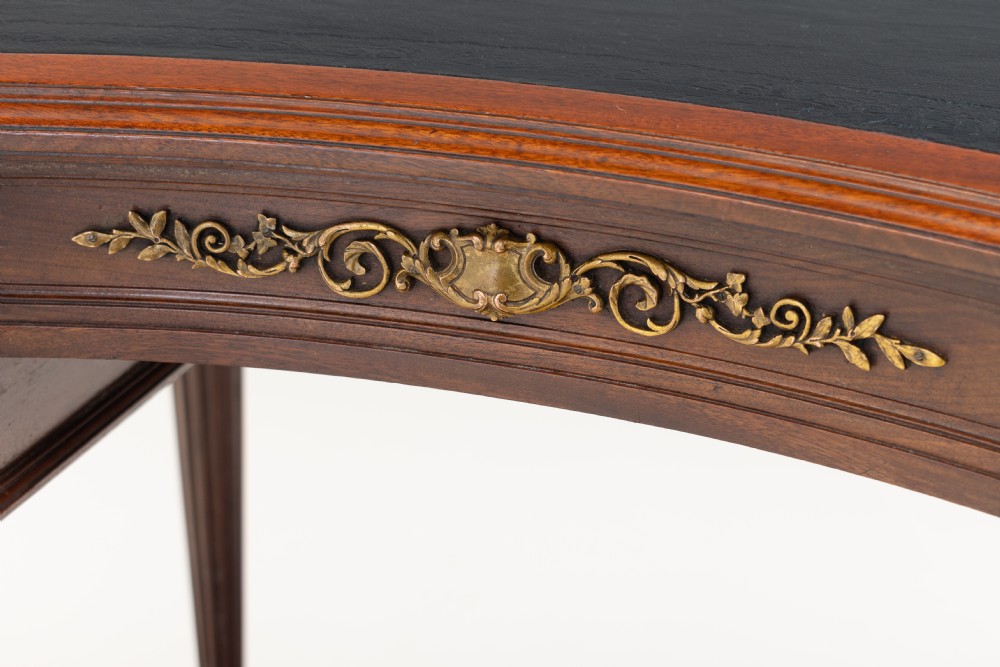 A mahogany kidney-shaped writing desk with a dark leather inset top, gilt-bronze mounts, four side drawers, and fluted legs joined by a curved stretcher. View VI